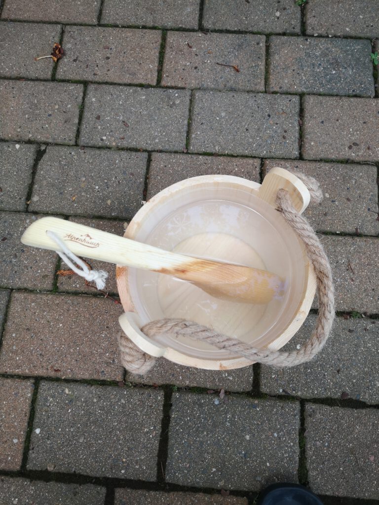 Saunaeimer mit Kelle auf Plastersteinen